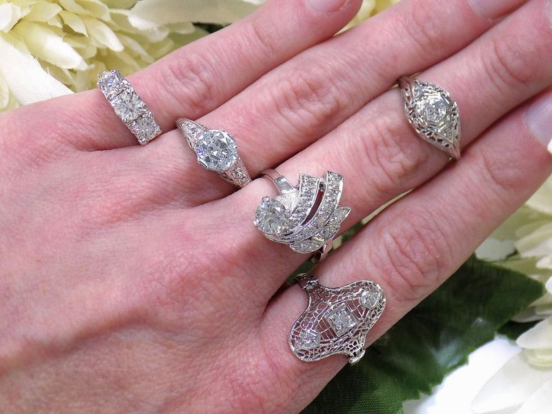 Hand displaying six ornate diamond rings of various designs
