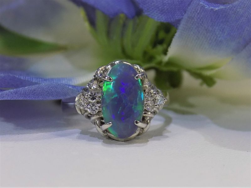 Oval opal and diamond ring with a blue and green iridescence,