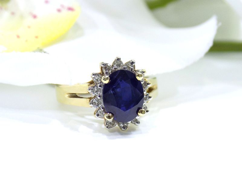 Gold ring with oval sapphire center stone and diamond halo