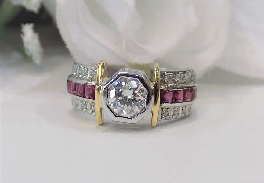 Diamond and ruby ring with gold accents on a white surface
