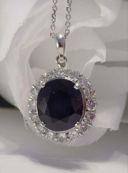 Silver pendant necklace with dark blue gemstone surrounded by white gems