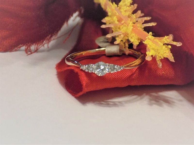 Gold ring with three clear stones on red fabric