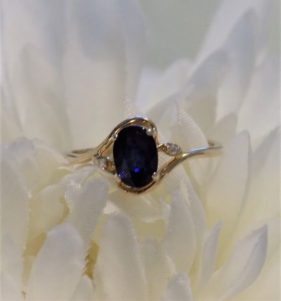 Gold ring with a blue oval sapphire and two small diamonds
