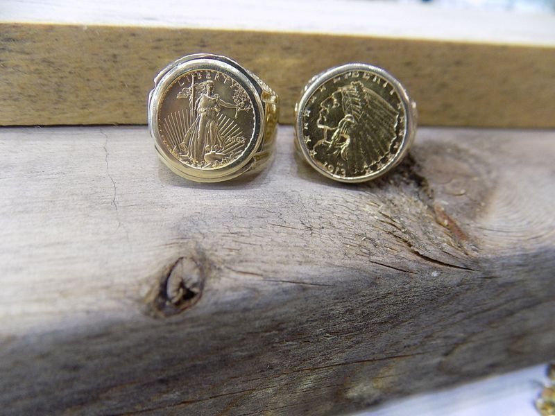 Two gold coin rings on a wooden surface