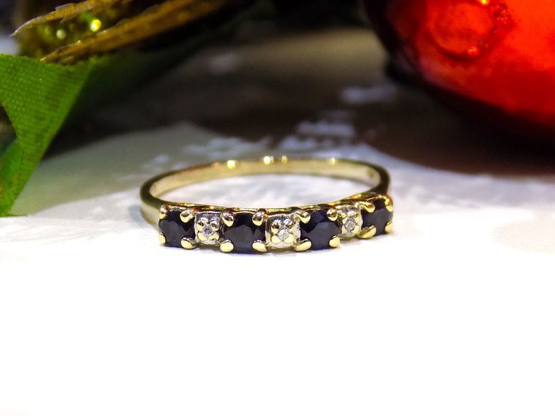 Gold band ring with alternating dark blue and clear stones