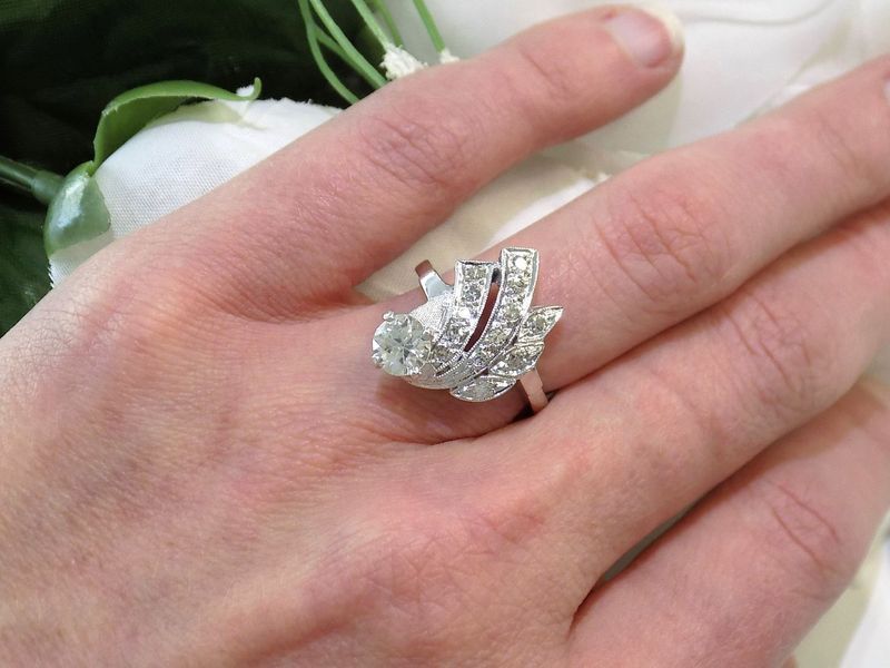 Hand wearing a diamond ring with a unique floral design