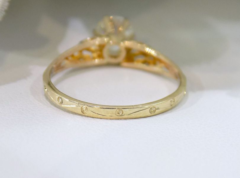 Gold ring with a central stone and small decorative diamonds