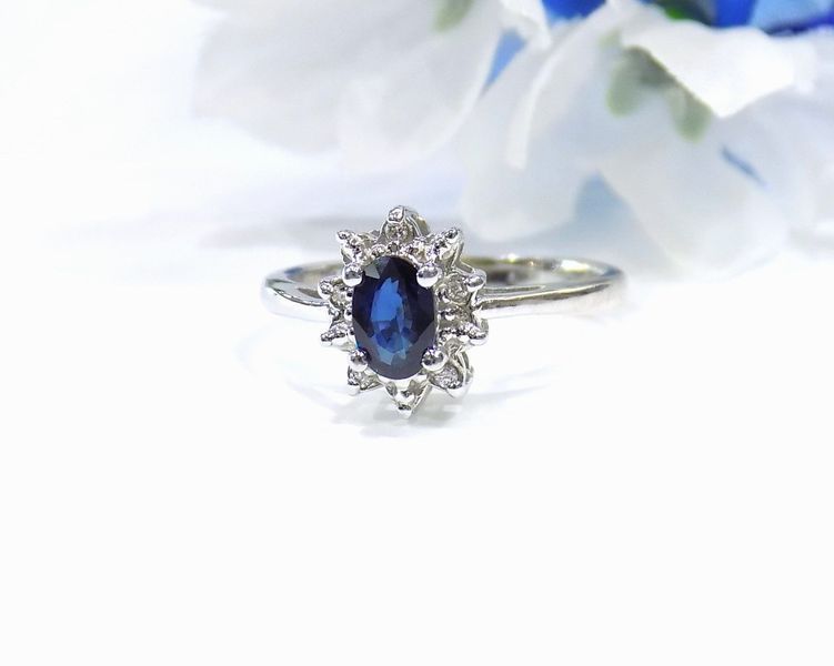 Oval sapphire and diamond halo ring on a white background