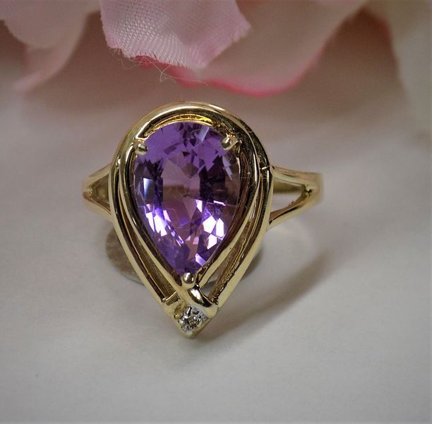 Gold ring with a large, pear-shaped purple amethyst and a small diamond accent