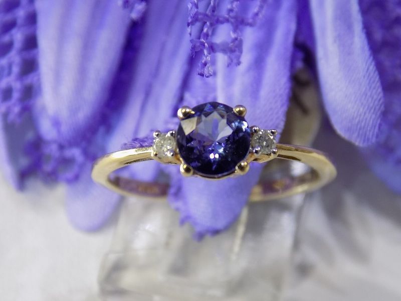Gold ring with a purple oval gemstone and two smaller white stones