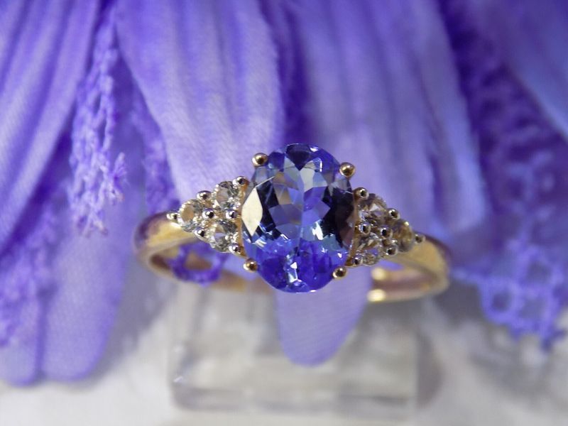 Gold ring with oval blue gemstone and two clusters of small white gems