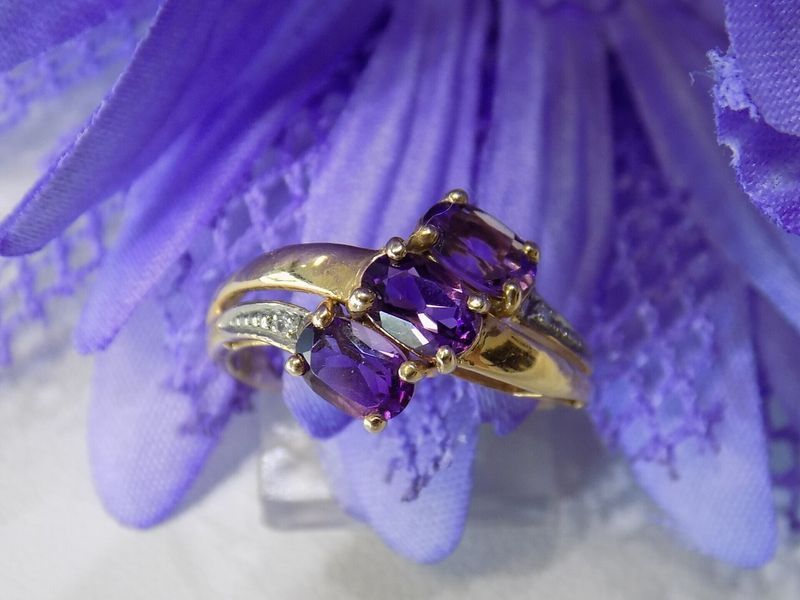 Gold ring with three purple amethyst stones on a purple flower