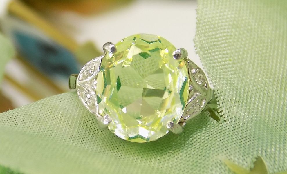 Ring with large, oval yellow-green gemstone and smaller white accent stones
