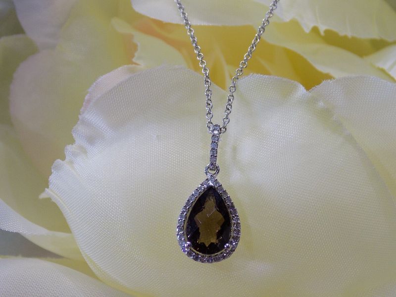 Silver necklace with a pear-shaped brown gemstone pendant, surrounded by small clear gems