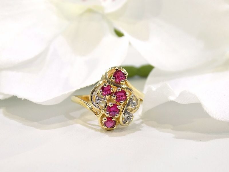 Gold ring with red and white gemstones in front of white flowers