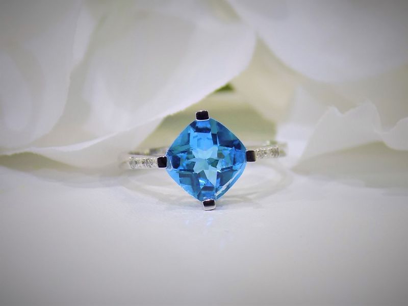 Blue topaz cushion-cut gemstone ring with a diamond-studded band