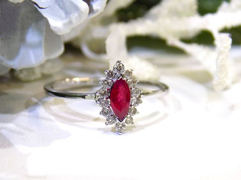 Marquise-cut ruby ring with diamond halo on white background