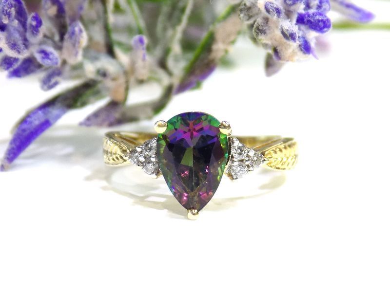 Gold ring with pear-shaped iridescent gemstone and two small diamond clusters