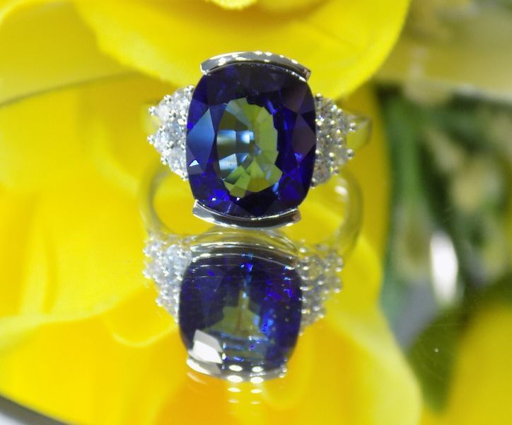 Blue gemstone ring with diamonds set on a yellow surface