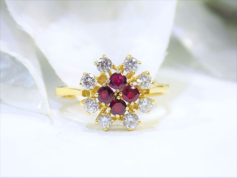 Gold ring with a flower-shaped cluster of red and white gemstones