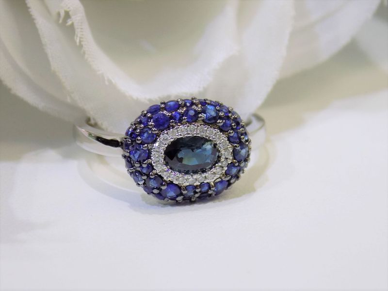 Oval sapphire ring with diamond halo on a white background