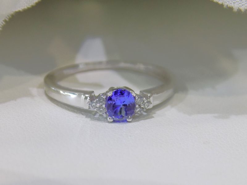 Silver ring with oval blue gemstone and two small white stones.