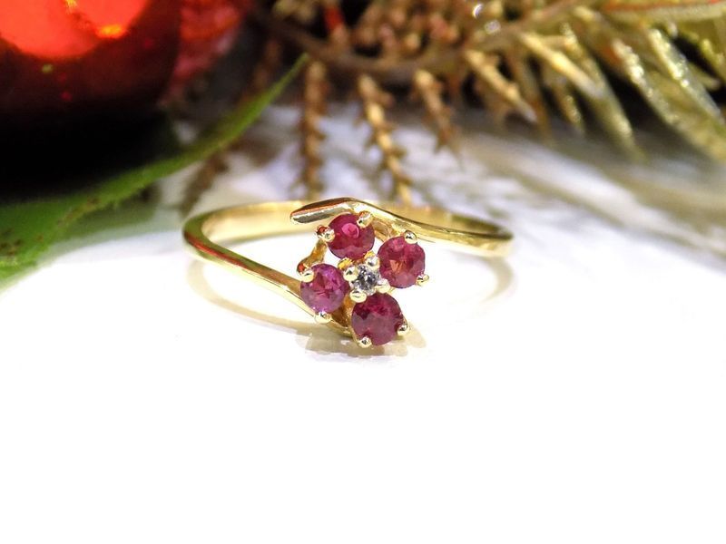 Gold ring with four red gemstones and a single clear gemstone on a white surface