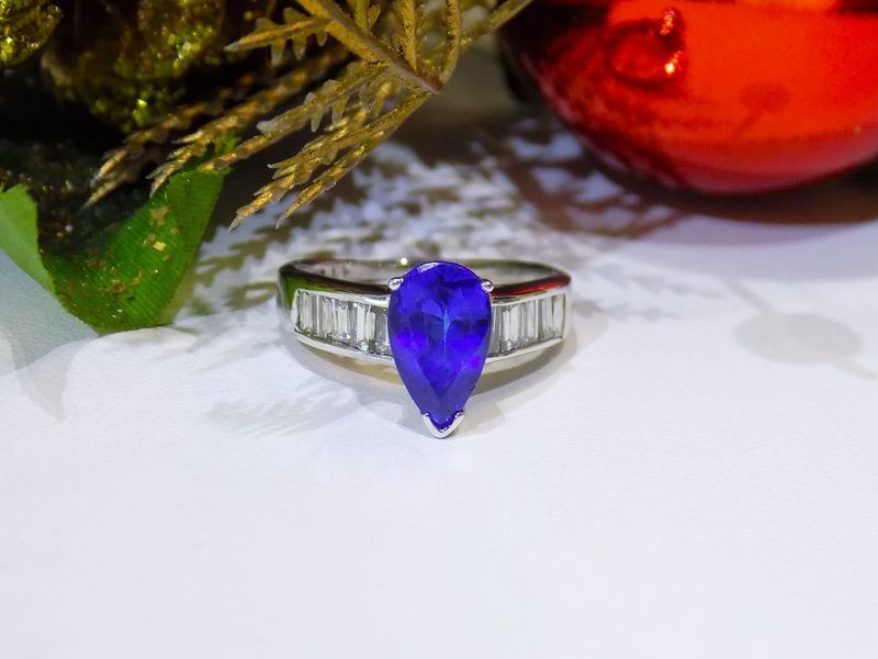 A blue pear-shaped gemstone ring with white-silver band and rectangular accents