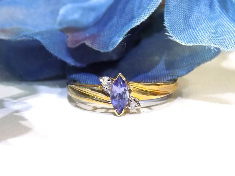 Ring with a marquise-cut purple gemstone, flanked by two white gems