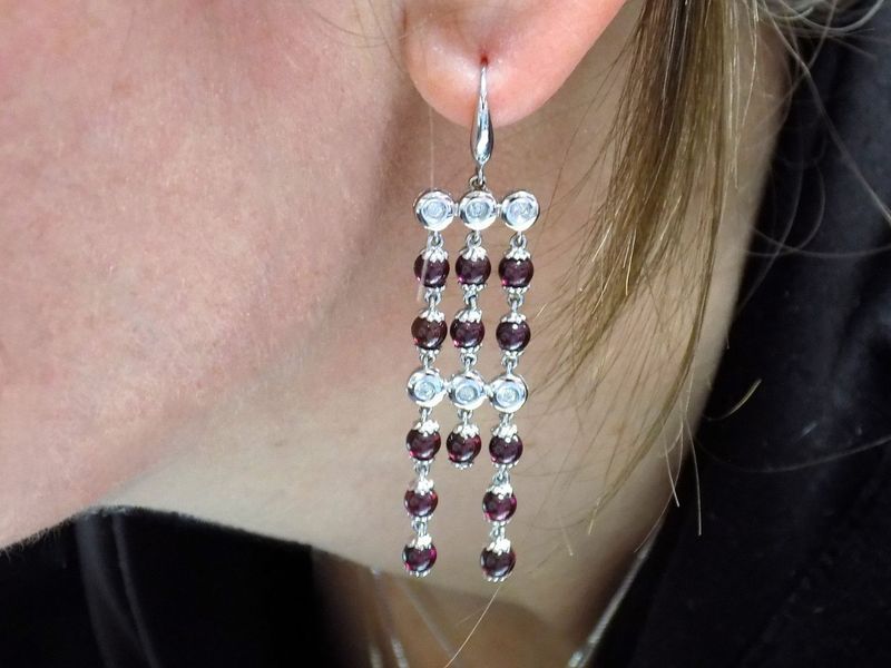 Woman wearing dangling earrings with white and maroon beads