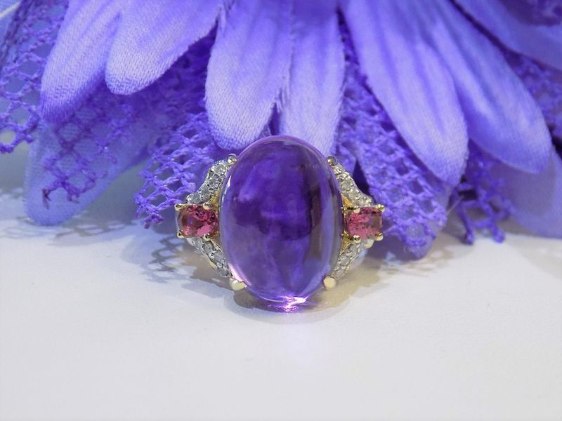 Purple gemstone ring with pink side stones on a purple flower