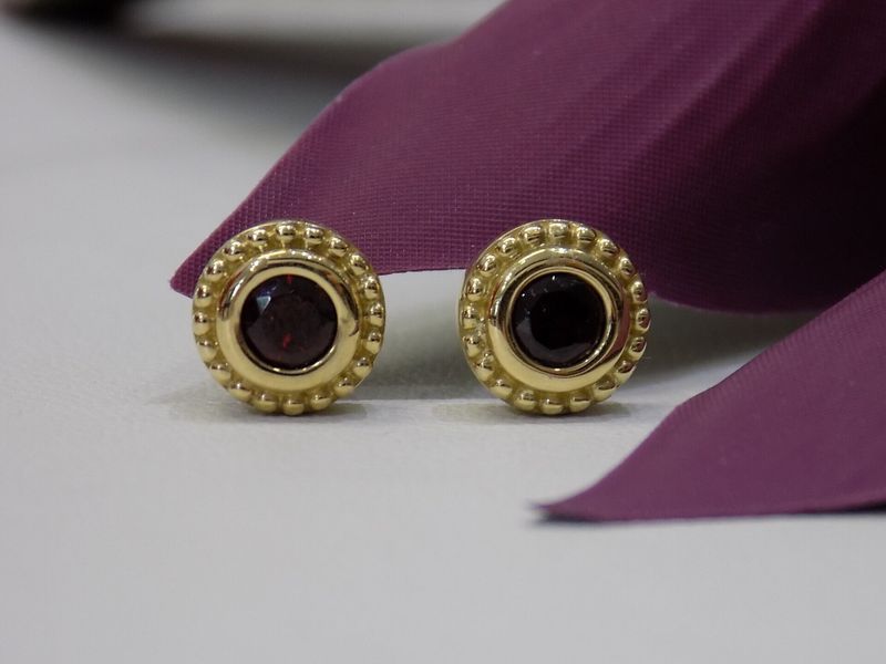 Gold stud earrings with dark red centers