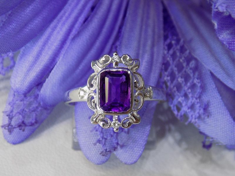 Purple amethyst ring with filigree design set against a soft purple flower