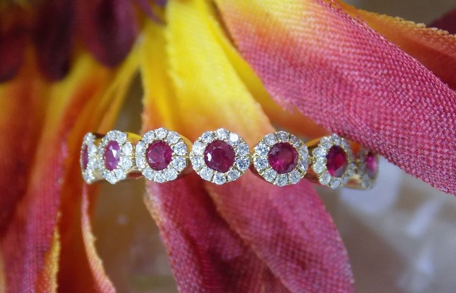 Gold ring with ruby and diamond halos, on burgundy and yellow flower petals