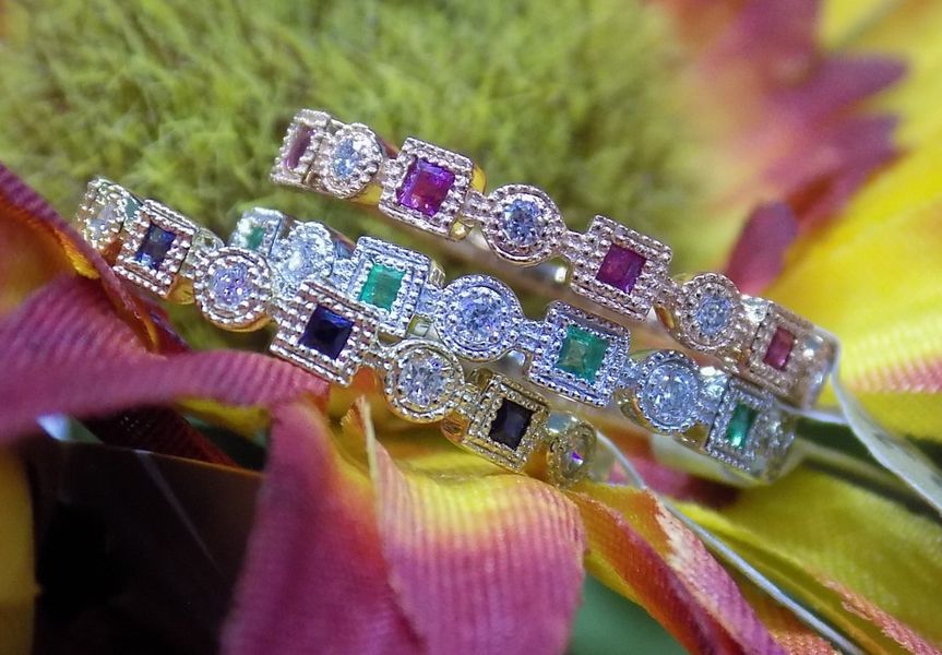 Three jeweled rings with colorful gemstones on a flower petal