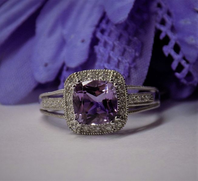 Amethyst ring with diamond halo against purple flower backdrop