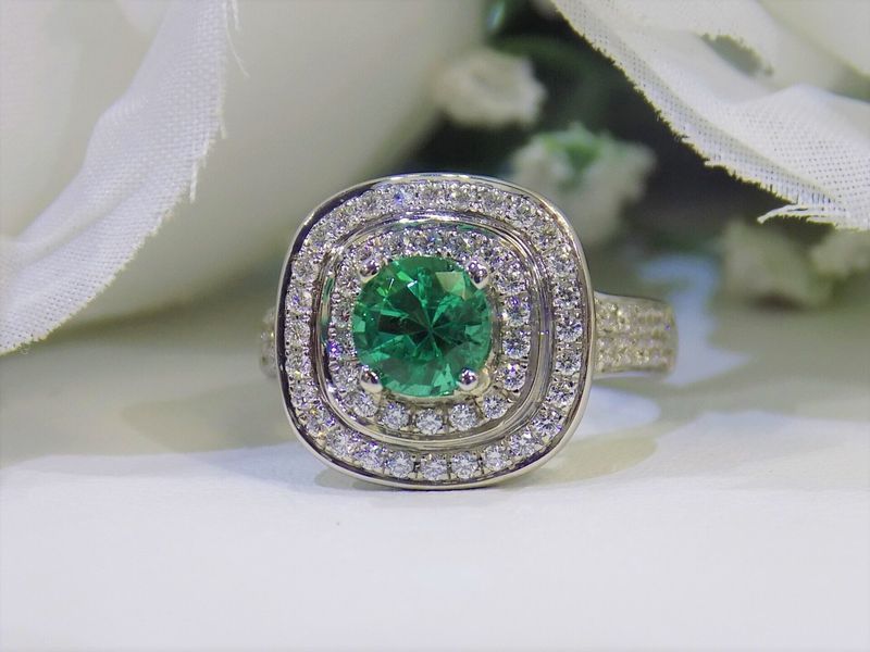 Emerald ring with double halo of diamonds, white background