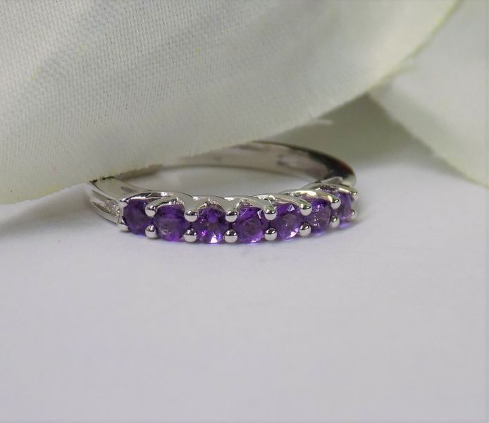 Silver ring with a row of small, round, purple gemstones