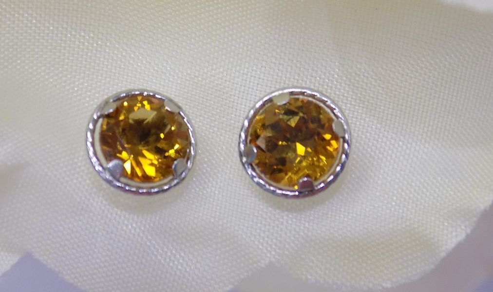 Two yellow gemstone stud earrings on a white surface