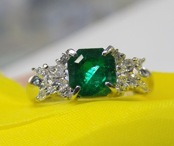 Emerald and diamond ring on yellow fabric
