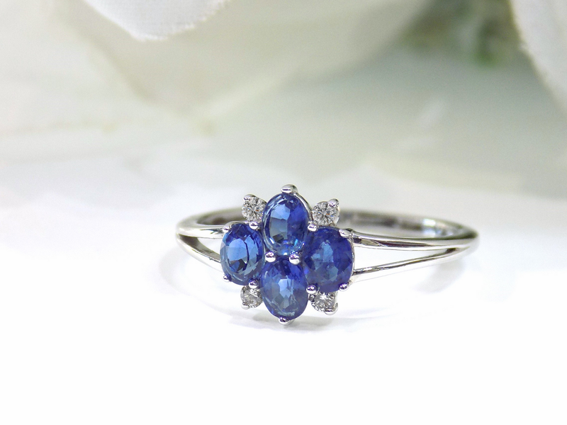 A silver ring with five blue oval sapphires in a flower-like design and small diamonds