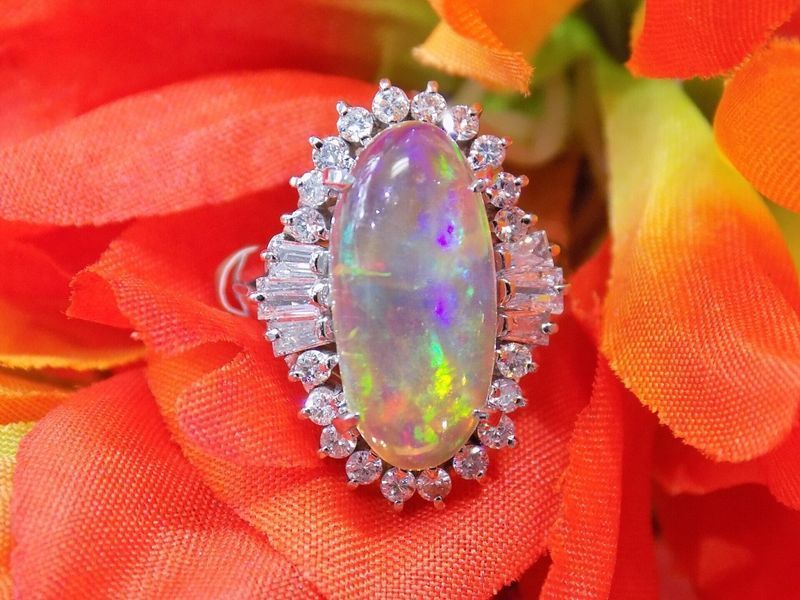 Oval opal ring with diamond halo set on orange flowers