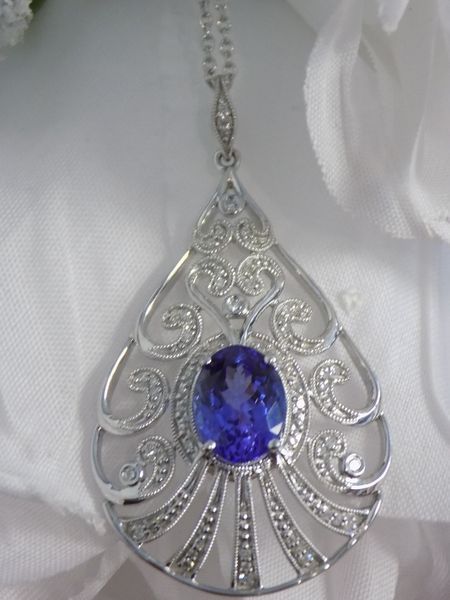 Silver pendant with a large, oval, blue gemstone and diamond accents