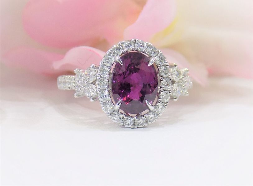 Oval-cut pink gemstone ring with diamond halo and side stones