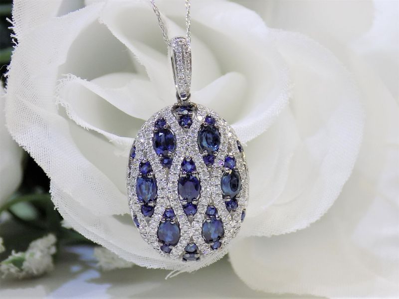 Oval sapphire and diamond pendant necklace on a white flower