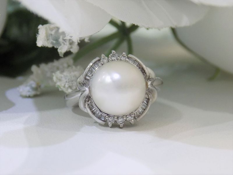 Pearl ring with surrounding small diamonds on a white surface