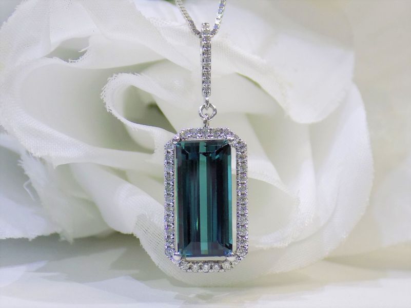 Emerald cut teal gemstone pendant with a diamond halo