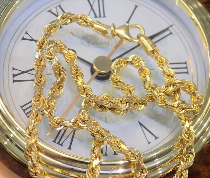 Gold rope chain draped on a clock with Roman numerals