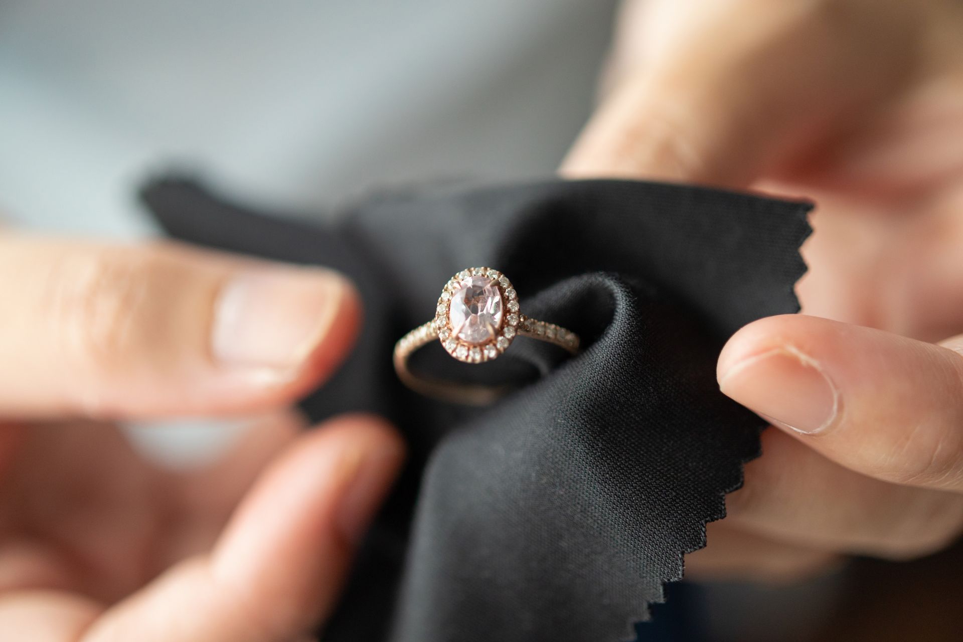 Person polishing a rose gold ring with a pink gemstone