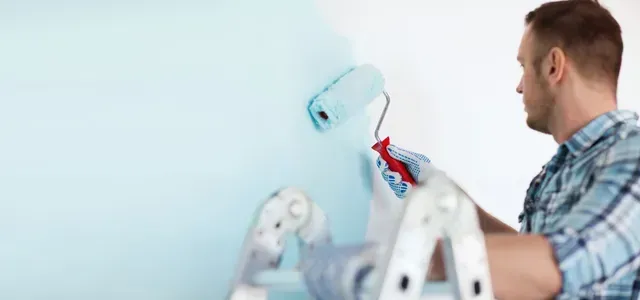 Close-up of male in gloves holding painting roller for residential painting project